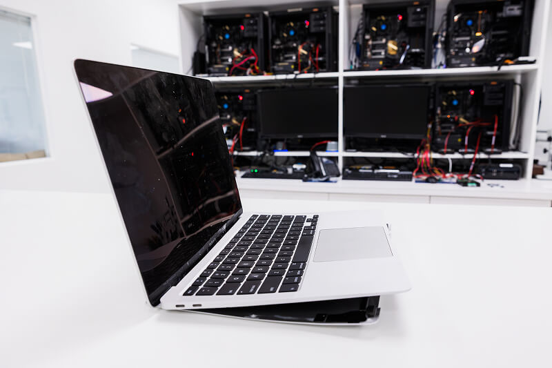 An image of a damaged MacBook in a data recovery lab.